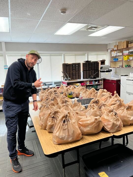 A FeedTahoe volunteer packing bags of rescued food on a long table